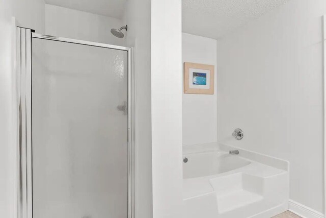 bathroom featuring a textured ceiling and plus walk in shower