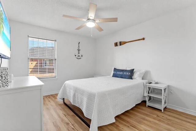 bedroom featuring ceiling fan, a textured ceiling, and light hardwood / wood-style floors