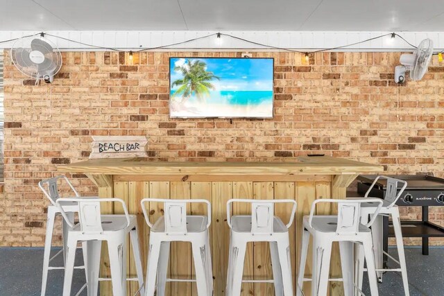 kitchen featuring brick wall and a breakfast bar area