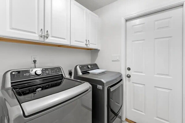 washroom with washing machine and dryer and cabinets