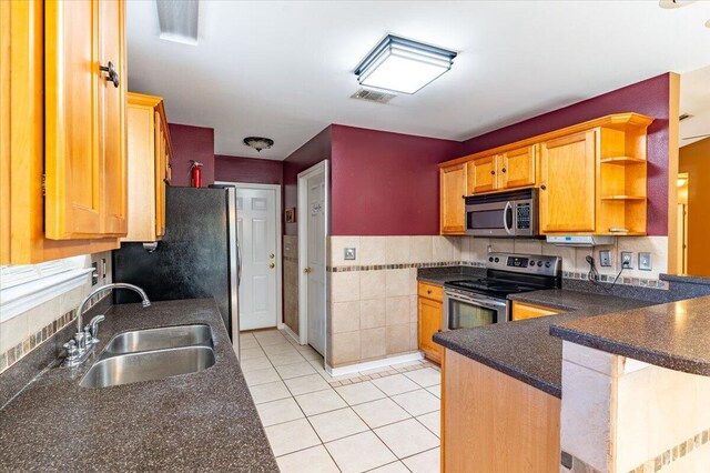 3968 Hickory St, Niceville, FL 32578 - kitchen with a peninsula, tile walls, a sink, light tile patterned floors, and stainless steel appliances