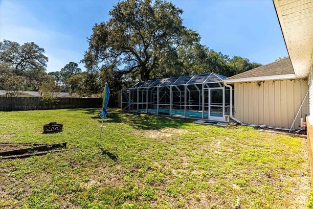 3968 Hickory St, Niceville, FL 32578 - view of yard featuring glass enclosure, a swimming pool, a fire pit, and a fenced backyard