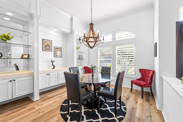 dining space featuring ornamental molding, light wood-type flooring, and a chandelier