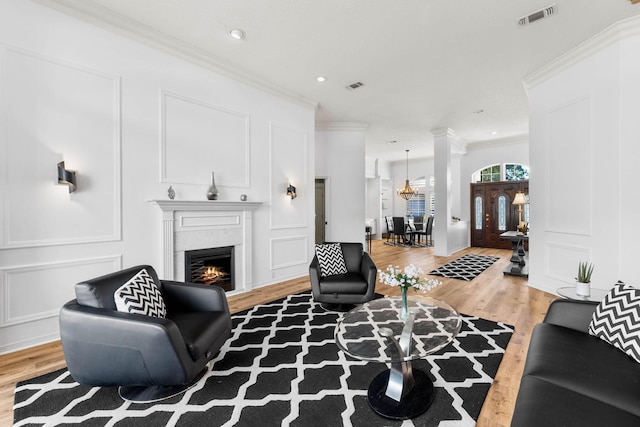 living area featuring visible vents, a decorative wall, a lit fireplace, and light wood-type flooring