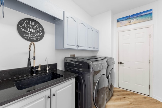 clothes washing area with cabinets, sink, light hardwood / wood-style flooring, and washer and dryer