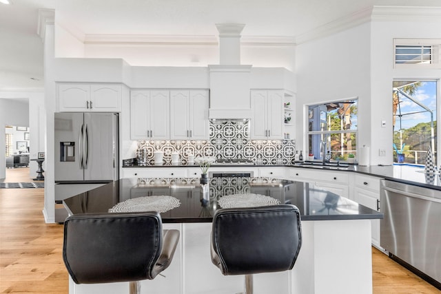 kitchen with a kitchen island, appliances with stainless steel finishes, light wood-type flooring, and white cabinetry