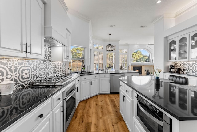 kitchen with light wood-type flooring, white cabinetry, a sink, backsplash, and stainless steel appliances