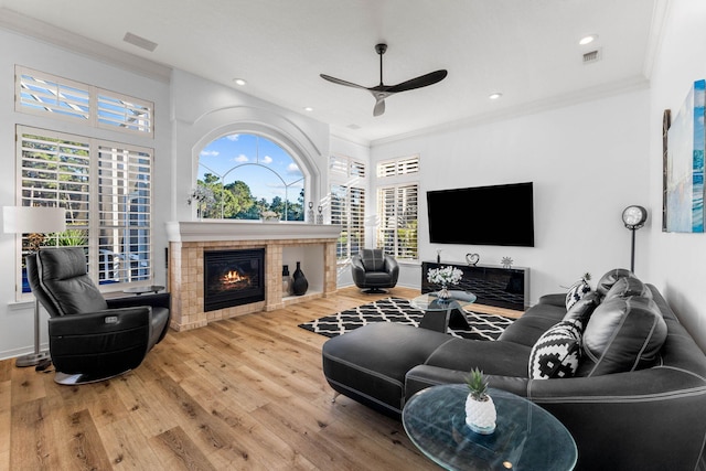 living room with ceiling fan, visible vents, ornamental molding, and a tile fireplace