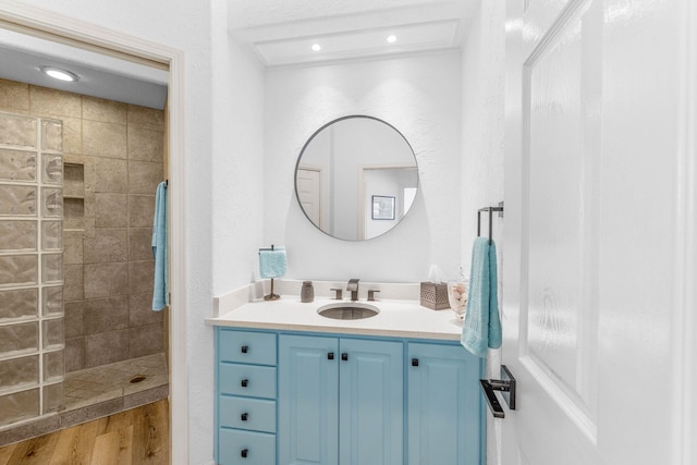 bathroom with a tile shower, hardwood / wood-style flooring, and vanity