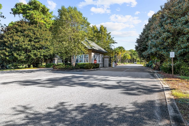 view of road featuring a gated entry, traffic signs, and curbs