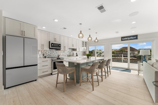 kitchen with sink, a breakfast bar, stainless steel appliances, a center island, and light wood-type flooring