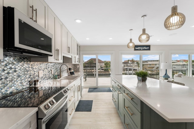 kitchen featuring light hardwood / wood-style flooring, decorative light fixtures, sink, stainless steel appliances, and white cabinetry