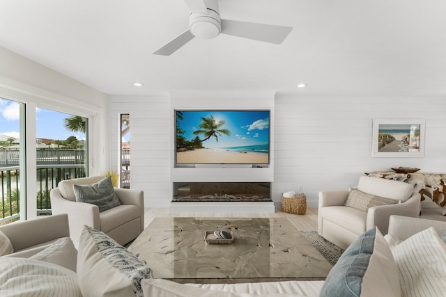 living room featuring wood walls, wood-type flooring, and ceiling fan