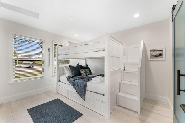 bedroom with a barn door and light hardwood / wood-style flooring