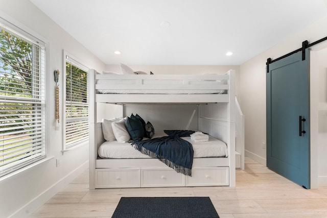 bedroom with a barn door and light hardwood / wood-style floors