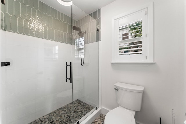 bathroom with a shower with door and toilet