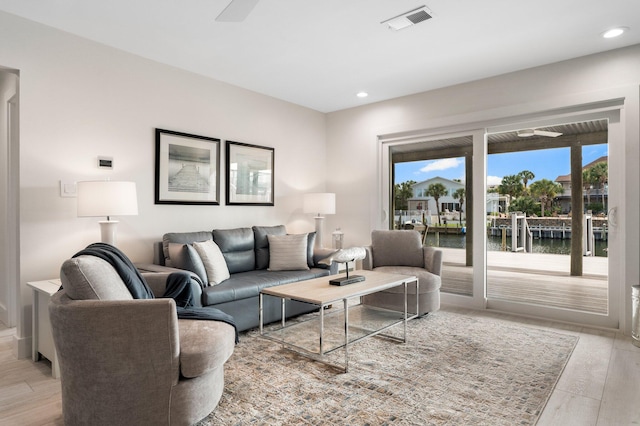 living room featuring a water view and light hardwood / wood-style flooring