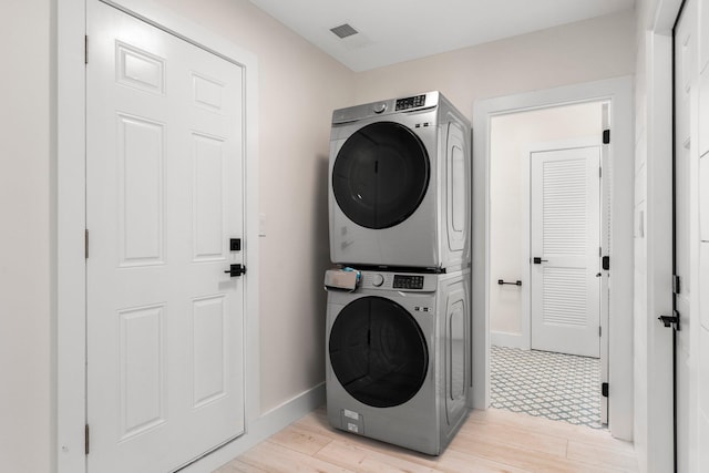 washroom with stacked washer / dryer and light hardwood / wood-style floors