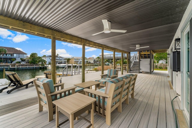 wooden deck featuring ceiling fan, a dock, and a water view