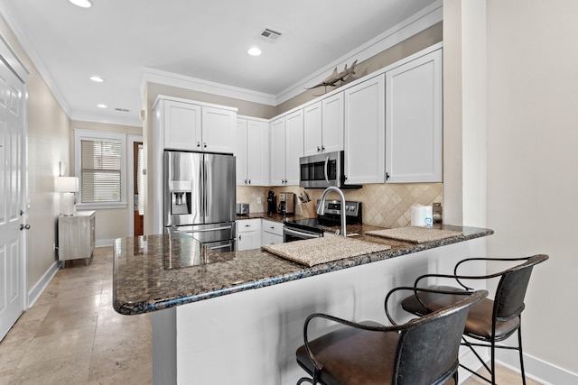 kitchen featuring kitchen peninsula, white cabinetry, stainless steel appliances, and a breakfast bar