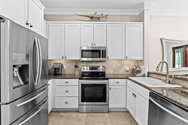 kitchen featuring tasteful backsplash, dark stone countertops, sink, appliances with stainless steel finishes, and white cabinetry