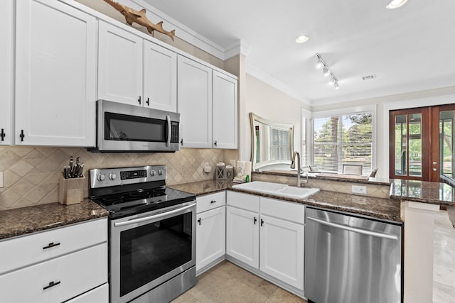 kitchen featuring dark stone countertops, white cabinets, appliances with stainless steel finishes, and sink