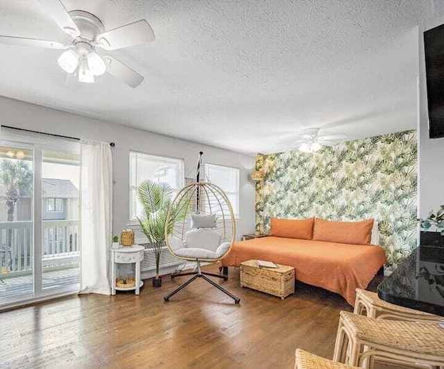 living room with ceiling fan, dark hardwood / wood-style floors, and a textured ceiling