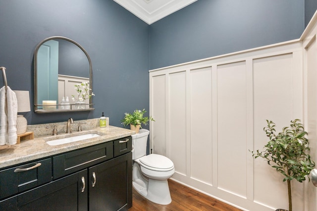 bathroom with toilet, ornamental molding, vanity, and hardwood / wood-style floors