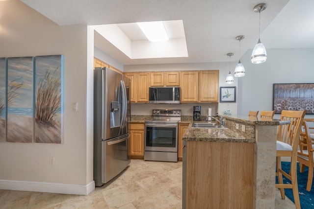 kitchen featuring hanging light fixtures, sink, kitchen peninsula, stainless steel appliances, and a breakfast bar