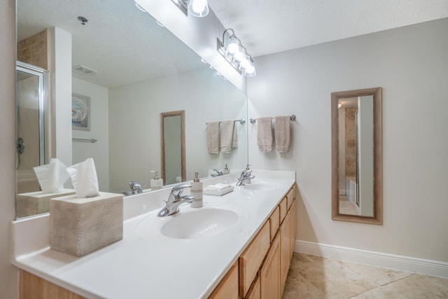 bathroom with tile patterned floors, a shower with door, vanity, and a textured ceiling