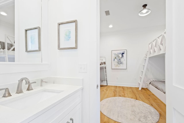 bathroom featuring vanity, hardwood / wood-style flooring, and crown molding