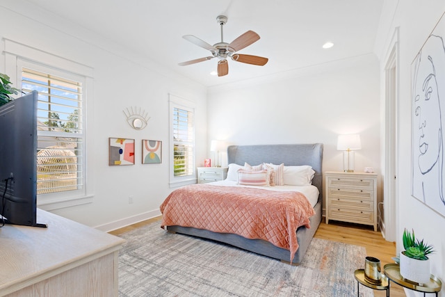 bedroom featuring ceiling fan, crown molding, light hardwood / wood-style floors, and multiple windows