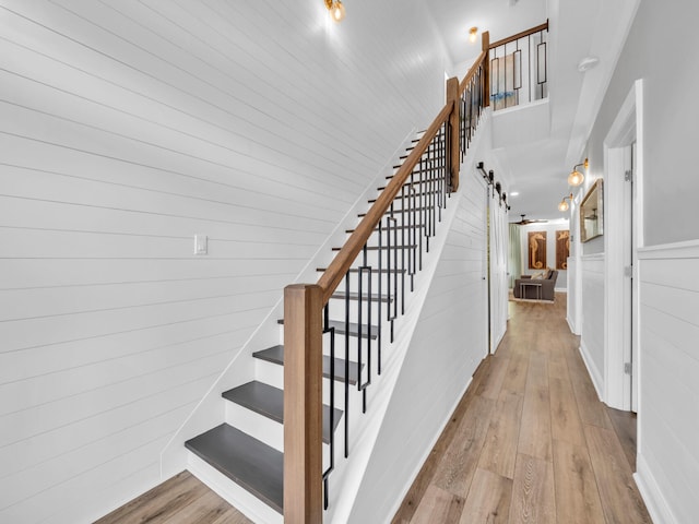 staircase with wooden walls, a barn door, and hardwood / wood-style floors