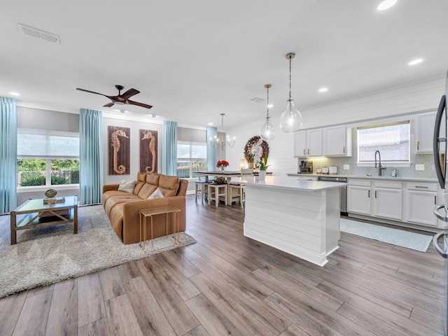 kitchen featuring light hardwood / wood-style flooring, white cabinets, a healthy amount of sunlight, and hanging light fixtures