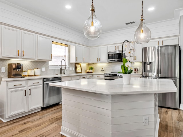 kitchen with sink, a center island, hanging light fixtures, and stainless steel appliances