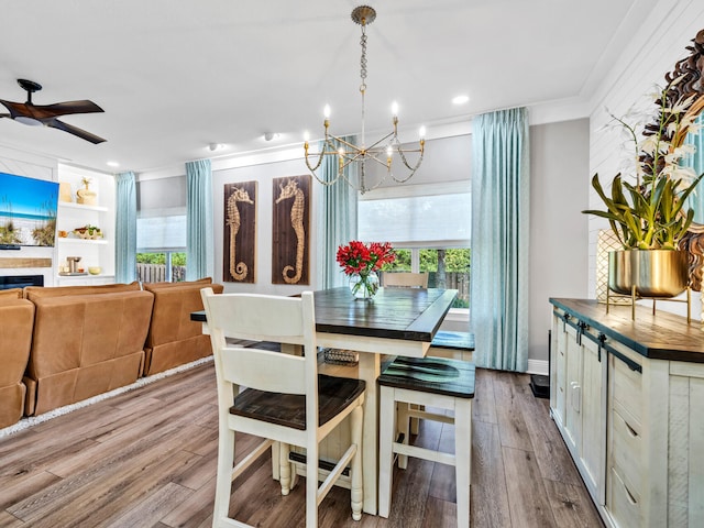 dining space featuring light hardwood / wood-style floors, crown molding, ceiling fan with notable chandelier, and plenty of natural light