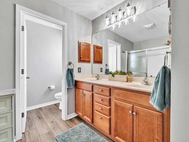 bathroom with vanity, a shower with shower door, hardwood / wood-style flooring, and toilet