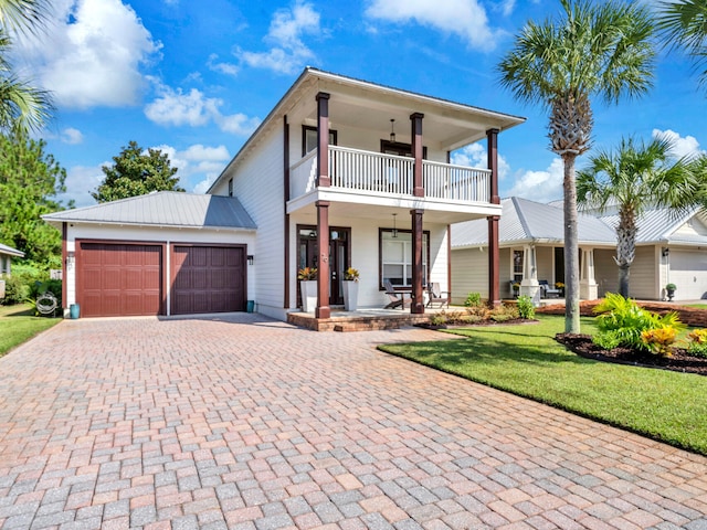 view of front of home featuring a balcony, a garage, a front lawn, and a porch