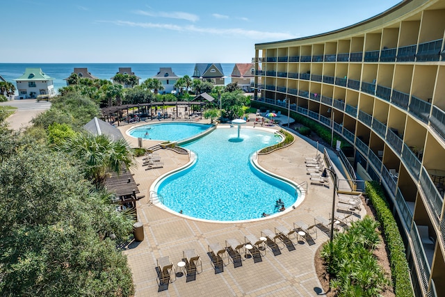 view of swimming pool with a water view, a patio, and pool water feature