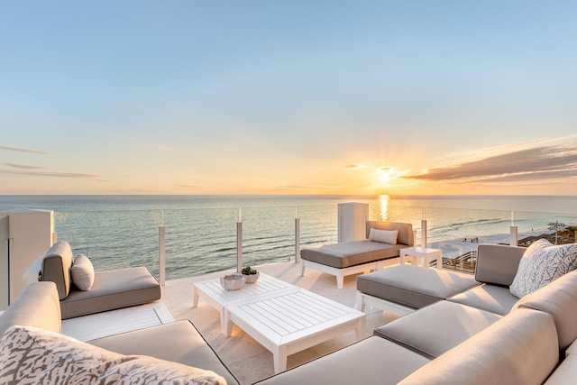 patio terrace at dusk featuring a water view and an outdoor living space