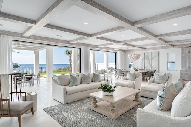 tiled living room with a notable chandelier, a water view, beamed ceiling, and coffered ceiling