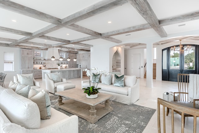 tiled living room featuring beamed ceiling, coffered ceiling, and an inviting chandelier