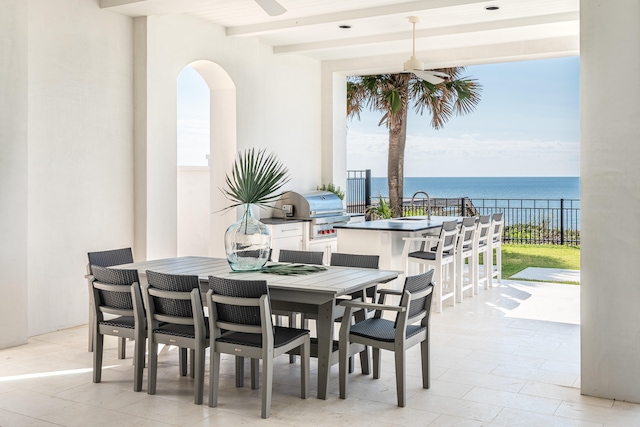 dining space with beamed ceiling, plenty of natural light, and a water view