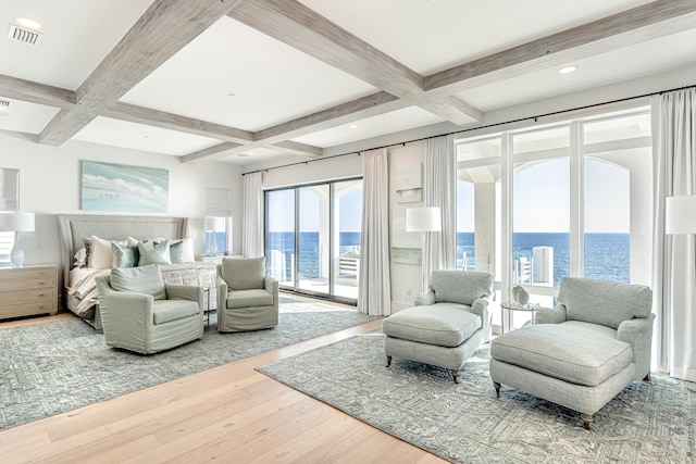 bedroom featuring wood-type flooring, beamed ceiling, access to exterior, and a water view