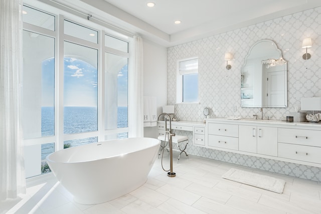 bathroom featuring a water view, a tub to relax in, and vanity