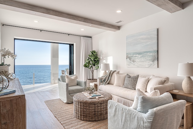 living room featuring a water view, beam ceiling, and light hardwood / wood-style floors