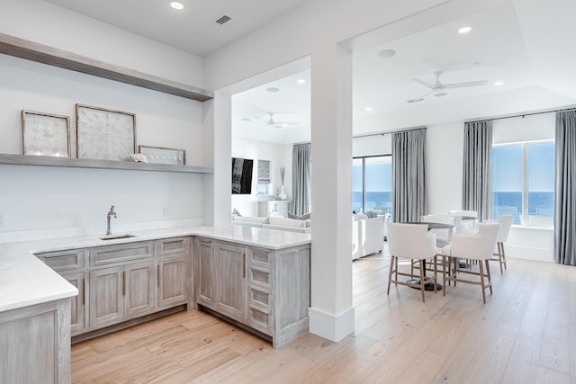 kitchen with light brown cabinetry, light wood-type flooring, a water view, and a wealth of natural light