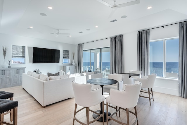 living room with a water view, light hardwood / wood-style floors, a wealth of natural light, and ceiling fan