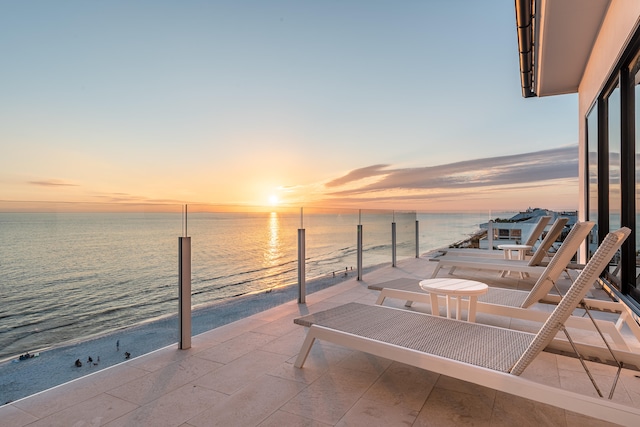 patio terrace at dusk featuring a water view