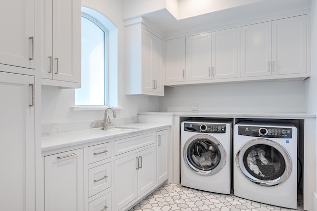 laundry room with cabinets, light tile patterned flooring, washer and dryer, and sink